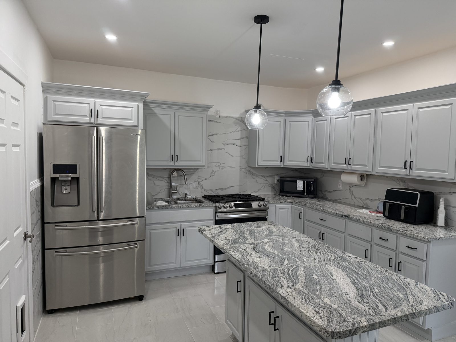 Fully remodeled kitchen with grey cabinets and a granite island