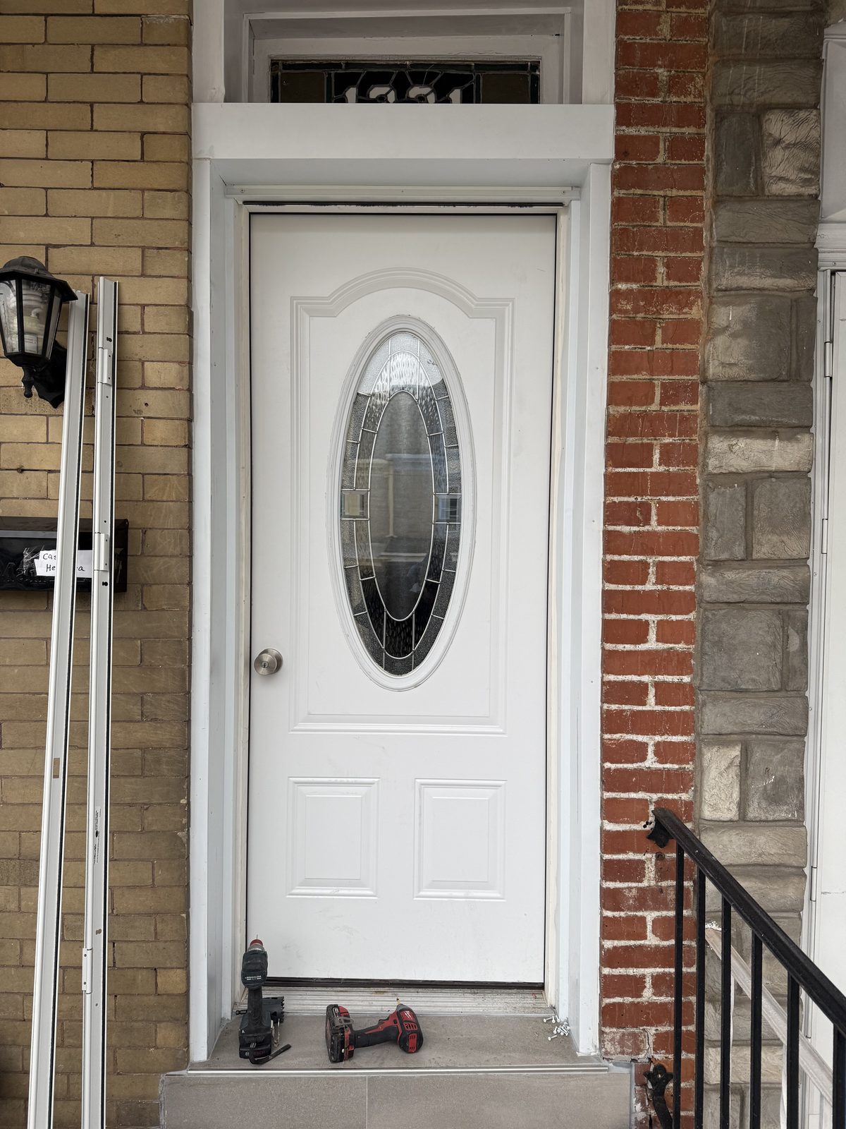White front door with oval glass installed in a brick facade